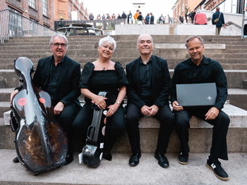 Fire musikere sitter i en trapp